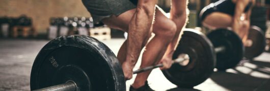 man and woman doing deadlifts in a gym