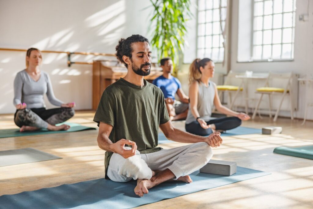 man doing yoga pose in a class