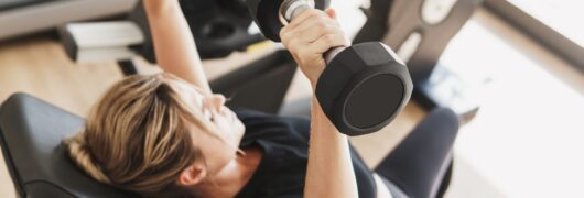 athletic woman doing bench press using dumbbells in gym